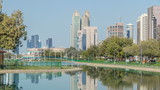 Fototapeta Miasto - Corniche boulevard beach park along the coastline in Abu Dhabi timelapse with skyscrapers on background.