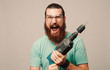 © Vulp - Young man with beard screaming holding a drill in hands.