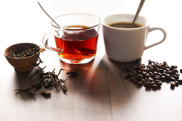 Coffee and tea with coffee bean and tea leaves on wooden floor.