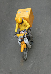  Delivery of consignments on motorbike. Motorcyclist rides with delivery in the large yellow box on street Ho Chi Minh city, Vietnam.