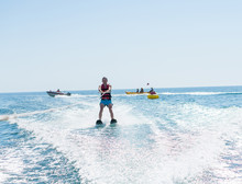 Young Man Glides On Water Skiing On The Waves On The Sea, Ocean. Healthy Lifestyle. Positive Human Emotions, Feelings, Joy.