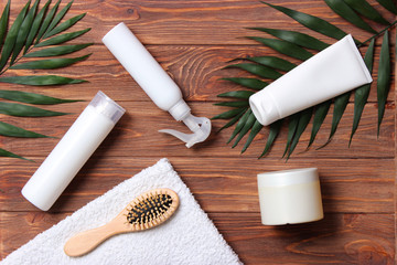 natural hair care products, hairbrush, towel and leaves on a wooden background top view. Shampoo, mask, balm. flatlay