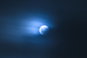 clouds moving over bright blue full moon