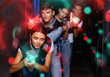Portrait of happy young friends playing laser tag  game  with la