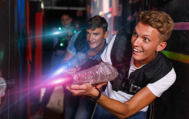 Wall Mural - Young guy holding colored laser guns and took aim during laser t