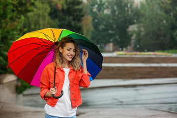 Wall Mural - Happy young woman with bright umbrella under rain outdoors