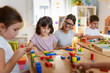 © lordn - Preschool teacher with children playing with colorful wooden didactic toys at kindergarten