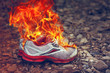 Burning Old Sneakers Or Shoes On Stone Surface Or Pebble Beach. Concept Of Passing Youth Or End Of Sports Career. Completion Of Tourist Trip Or Vacation. Pollution Of Nature With Fast Fading Things.