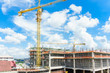 © navintar - Construction site. Construction cranes and high-rise building under construction against blue sky.