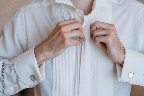 Fotografie, Obraz Male hands on a background of a white shirt, sleeve shirt with cufflinks and wat