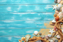 Sea Rope With Many Different Sea Shells On The Sea Sand On A Blue Wooden Background. Top View