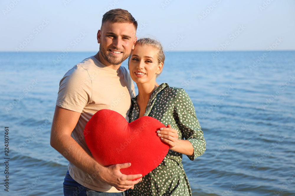 Cute young couple with red heart on sea shore