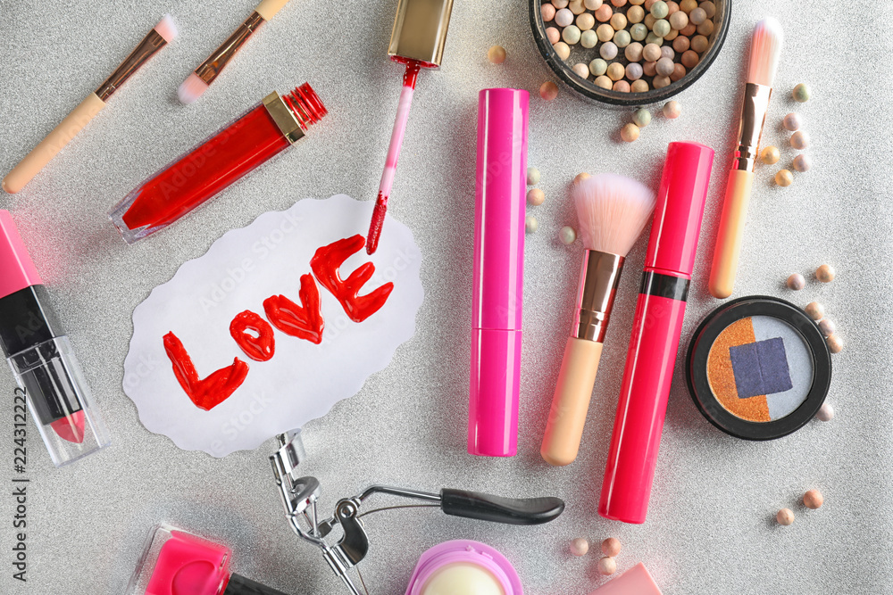 Set of cosmetics with word LOVE on grey background