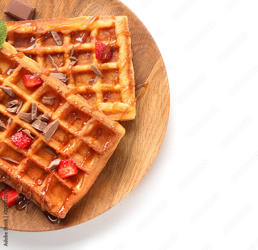 Delicious waffles with strawberries and caramel sauce on white background
