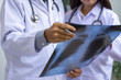 © NIKCOA - Two male and female doctors with stethoscope analyzing about chest x-ray film result of the patient. Medical consultant concept.
