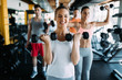 © NDABCREATIVITY - Young woman doing exercise with dumbbell in gym