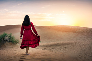 Girl walking in the desert at sunset