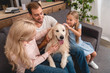© LIGHTFIELD STUDIOS - high angle view of parents with daughter playing with dog while sitting on couch at home