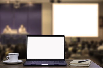 Wall Mural - Laptop computer with blank white screen mock up on people in meeting or conference room blurred background. Business seminar and education concept. clipping path and copy space for your text.