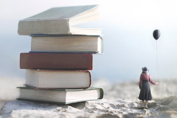 woman with balloon looks amazed at a mountain of giant books