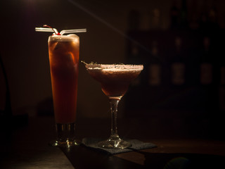 Cocktail in a beautiful glass on the table. In a dark bar