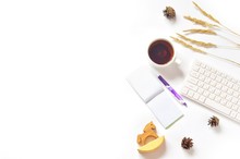 White Office Table Top View/ Cup Of Tea, Purple Pen, Notepad, Computer, Dry Autumn Herbs, Pine Cones And Wooden Toy Horse. Fall Season Mood And Minimalist Aesthetic