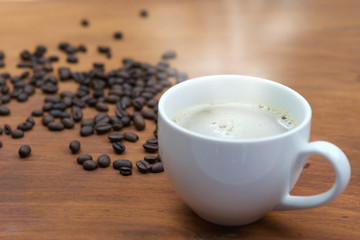 warm coffee cup and beans on wood background