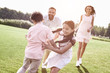 © Friends Stock - Bonding. Family of four running on grassy field playing playing