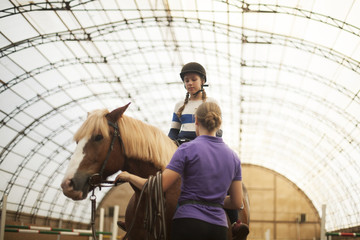 teen girl in helmet learning horseback riding