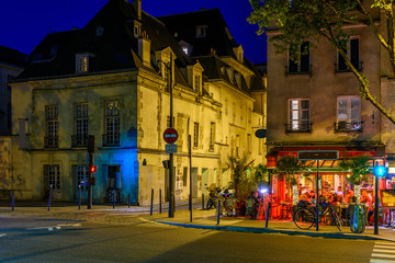 Cozy street with tables of cafe in Paris at night, France