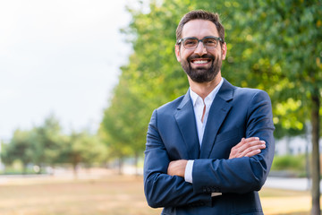 Portrait of confident businessman with crossed arms standing in the park