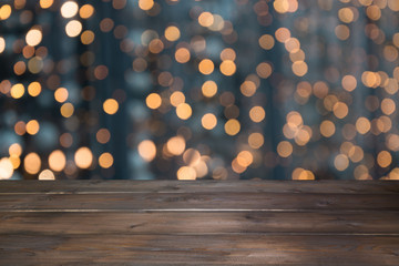 Blurred gold garland and wooden tabletop as foreground. Image for display or montage your christmas products.