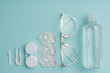 top view of eyeglasses and contact lenses storage objects arranged on blue background