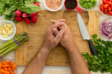 Man resting hands on wooden cutting board