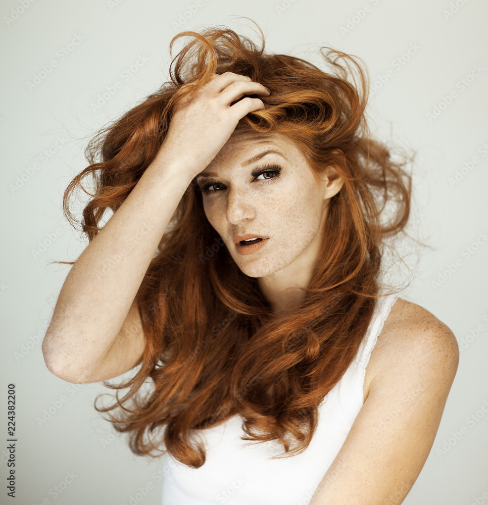 Portrait of a beautiful young woman with long red curly hair and ...