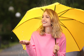 Wall Mural - Happy young woman with bright umbrella under rain outdoors