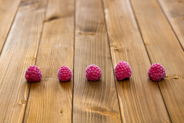 A row of frozen raspberries on a wooden background