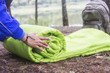 A woman folds and packs a sleeping bag, going on a journey through the forest. The concept of tourism and ecotourism. Equipment for traveling