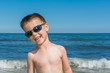 © nedomacki - a beautiful little boy posing on a beach by the sea with sunglasses