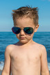 © nedomacki - a beautiful little boy posing on a beach by the sea with sunglasses