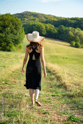 une femme de dos dans la campagne , en robe noire et un grand chapeau - Buy  this stock photo and explore similar images at Adobe Stock | Adobe Stock