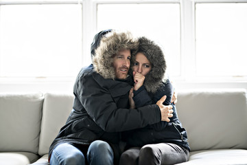 Couple have cold on the sofa at home with winter coat