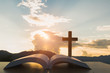 open Bible, script in blur with focus on palm cross,on sunrise background, Crucifix, Symbol of Faith.