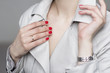 young woman with red nail polish wearing beige trenchcoat and silver wrist watches