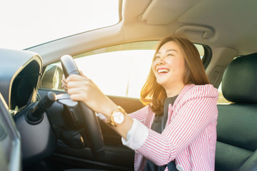 Happy confident and beautiful women,young asian businesswoman in casual wear,she smiling while driving a car against sunset rays Light shine sky Concept