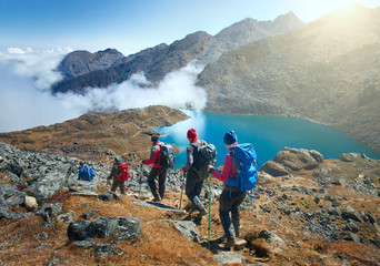 Group tourists with Backpacks descends down on Mountain Trail during Hike.