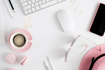 Trendy feminine home office workspace. White office desk. Laptop, coffee cup and macaroons, phone, hat, notebook, pencil. Flat lay, top view, copy space 