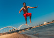 © Zoran Zeremski - Young man doing fitness workout at a beach on a sunny morning. Bare chested man running and jumping.