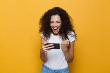 Happy Cute Young Woman Posing Isolated Over Yellow Background Play Games By Mobile Phone.