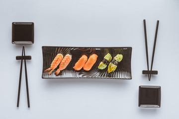 Wall Mural - top view of delicious sushi set and chopsticks isolated on white